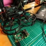 Drone assembly on a desk with laptop and tools, capturing modern tech.